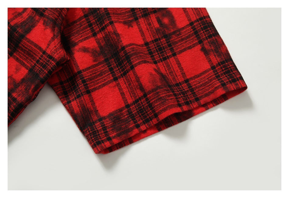 Close-up of the short sleeve and hem in a red-and-black plaid pattern.