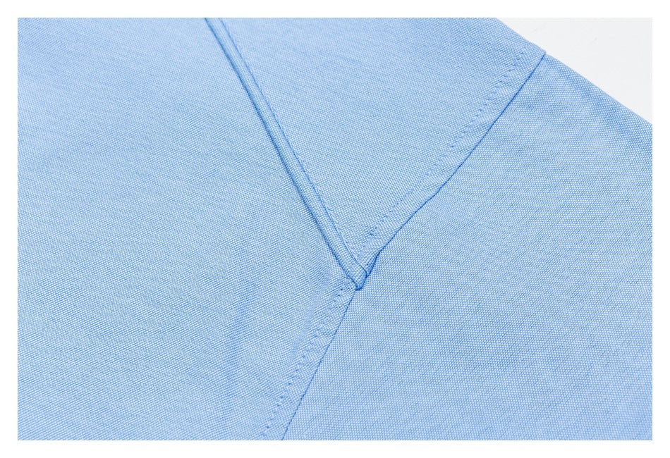Close-up of stitched seams on pale blue shirt fabric.