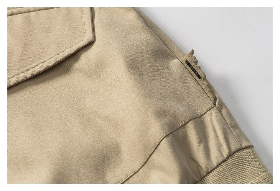 Close-up of a beige jacket side seam, small black garment tag, and rib-knit cuff.