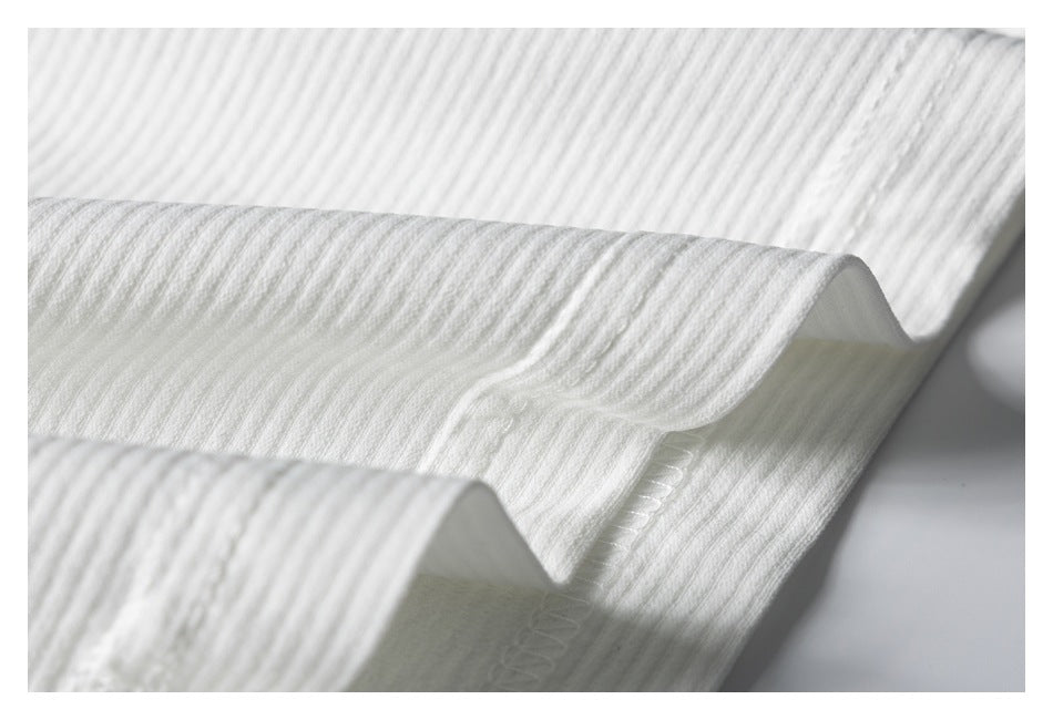 Close-up of white ribbed knit fabric folded to show a stitched edge.
