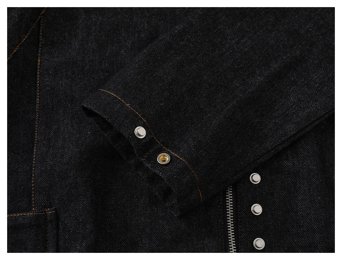 Close-up of a dark denim cuff with metal snaps, orange stitching, and part of a zipper.