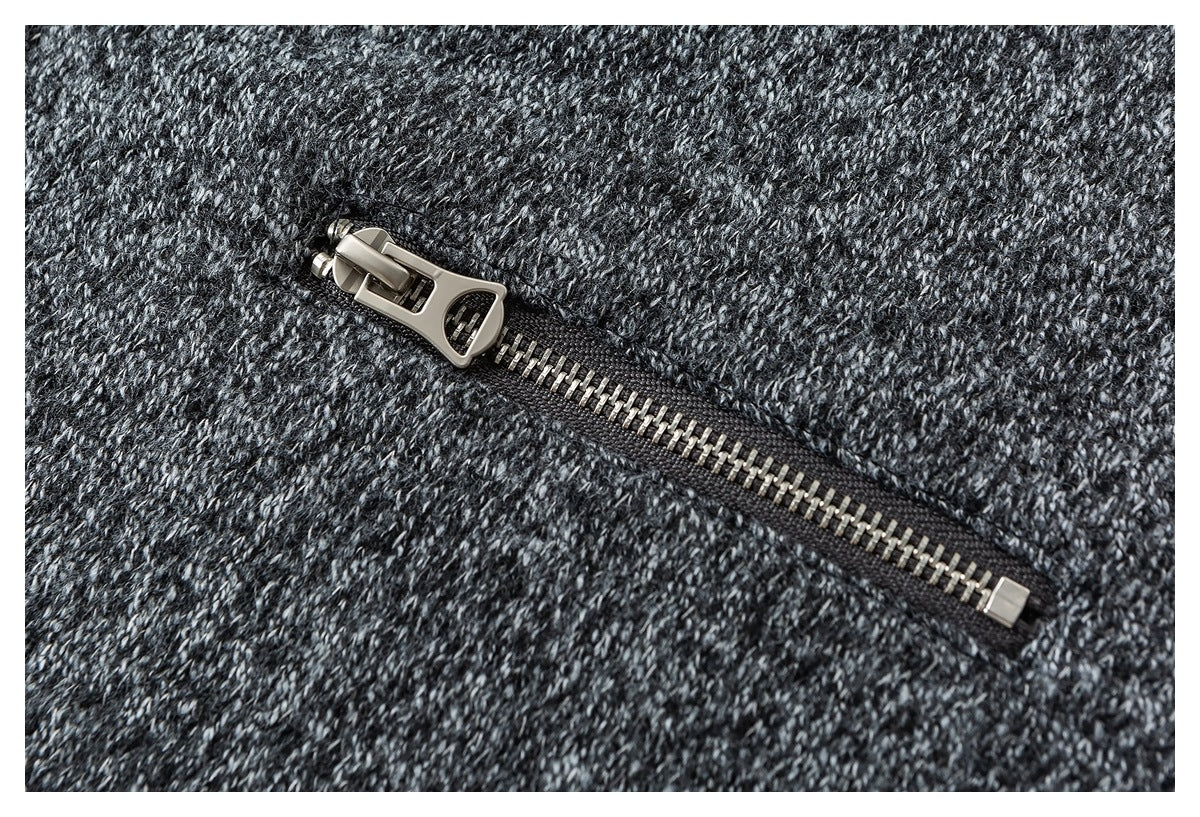 Close-up of a silver zipper on dark charcoal marled knit fabric.