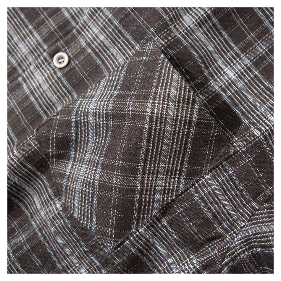 Close-up of a dark brown plaid shirt pocket and button.