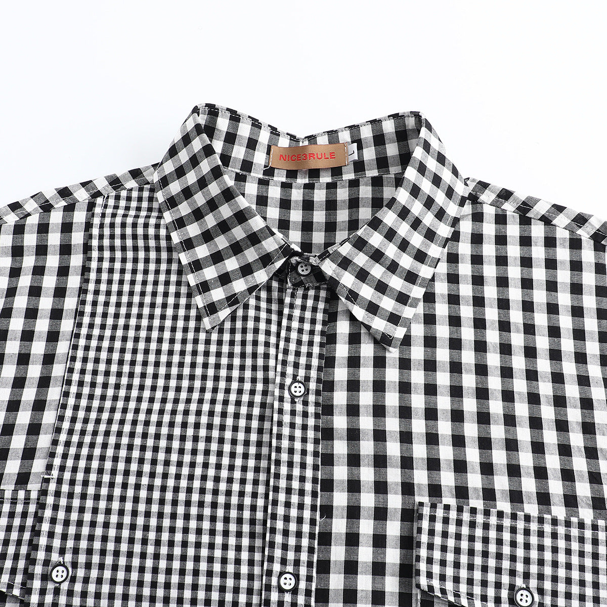 Close-up of a black-and-white check shirt showing its pointed collar, buttons, and contrasting check panels.