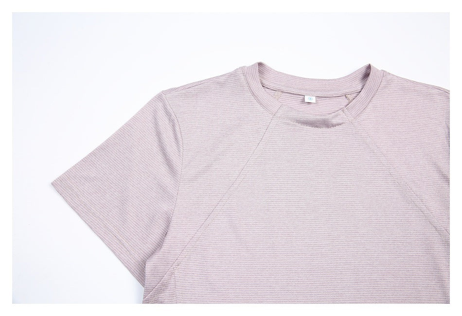 Close view of a pale mauve shirt's crew neckline, raglan seams, and fine repeating pattern.
