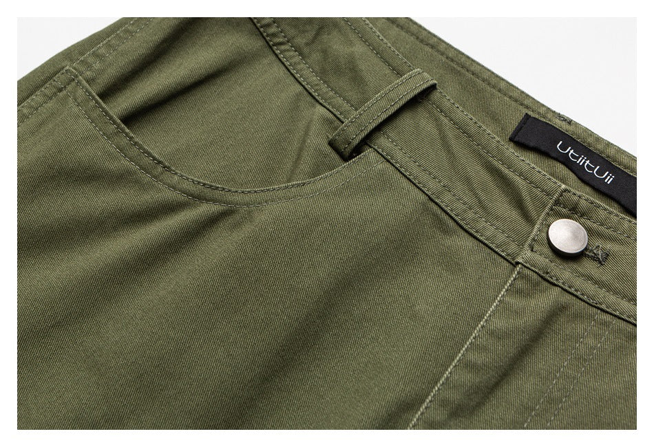 Olive-green trousers close-up showing a curved front pocket, belt loop, silver button, and sewn-in label.