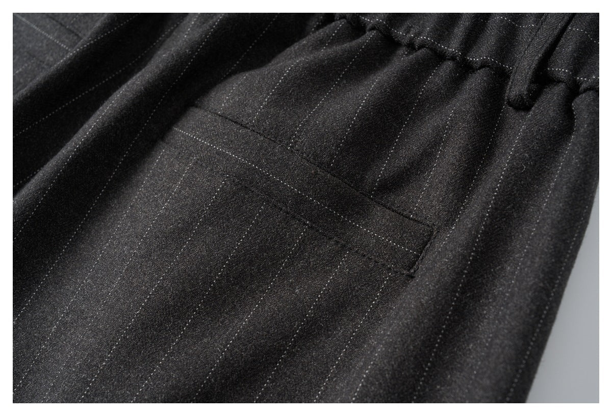 Close-up of a welt pocket and fine pinstripes on black trousers.