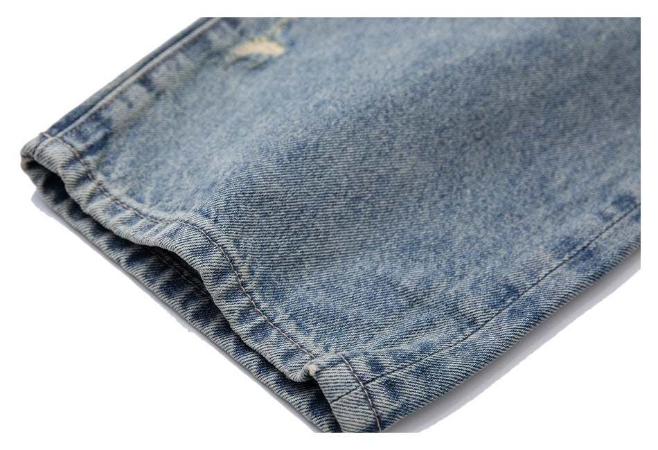 Close-up of a folded and stitched hem on faded light-blue denim.
