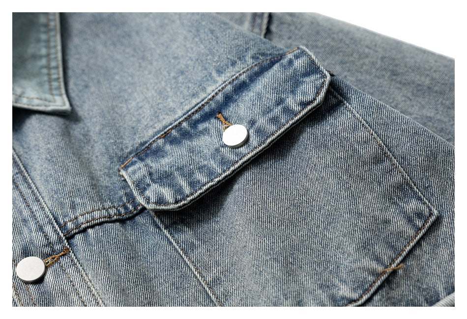 Close-up of a denim jacket chest pocket with a buttoned flap and contrast stitching.