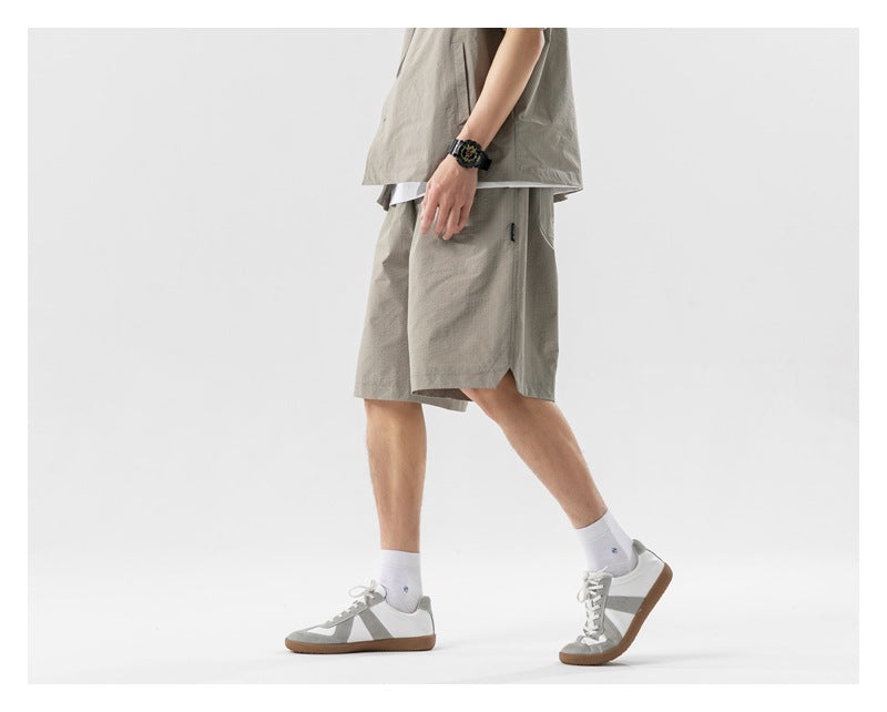 Side view of a cropped model wearing a taupe shirt and matching knee-length shorts.
