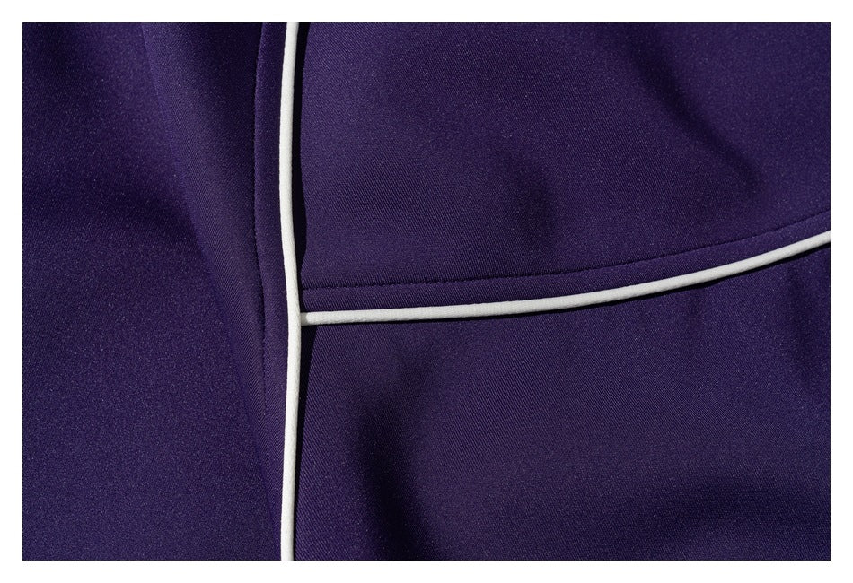 Close-up of white piping and seams on a purple jacket.