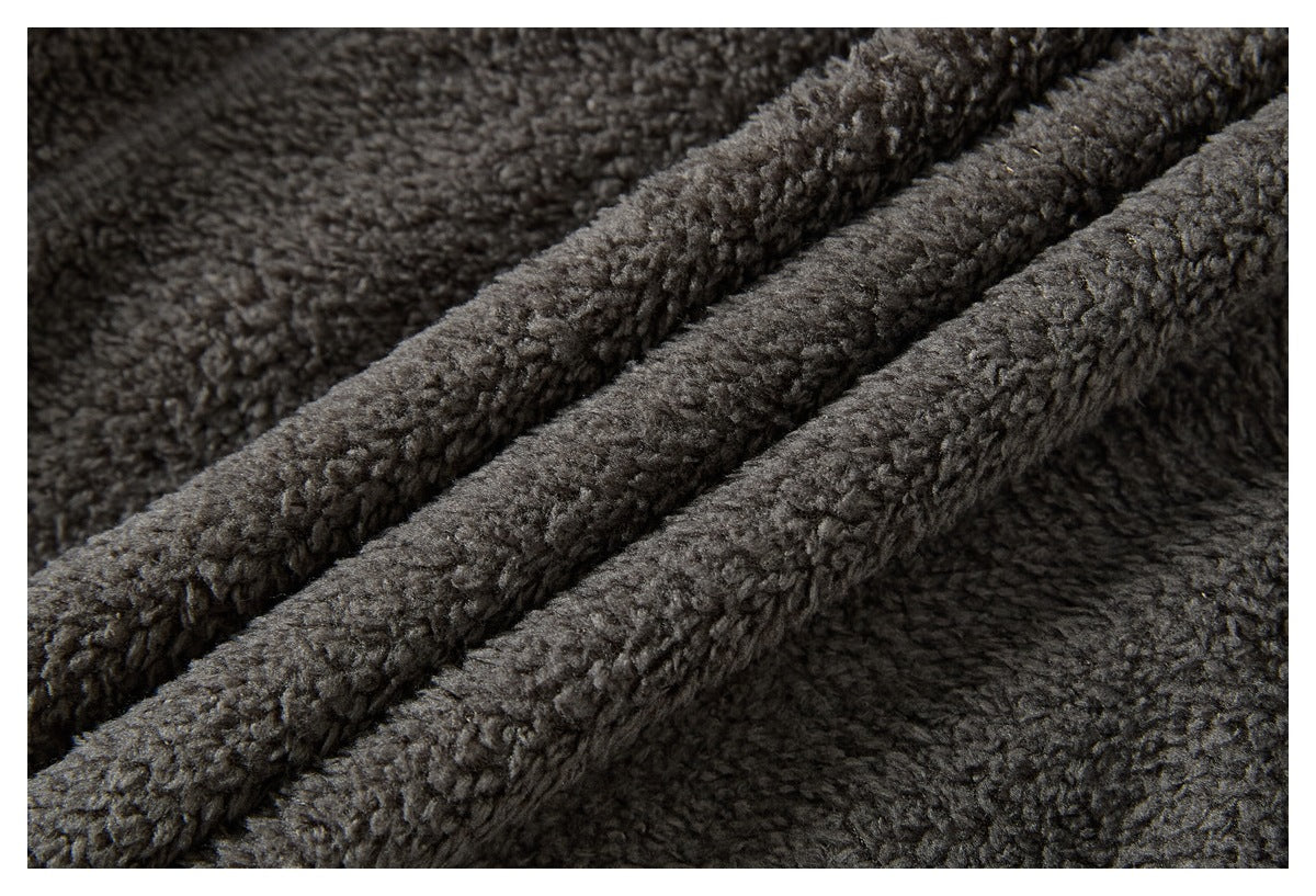 Close-up of dark gray plush fabric with a dense, curly pile and folded ridges.