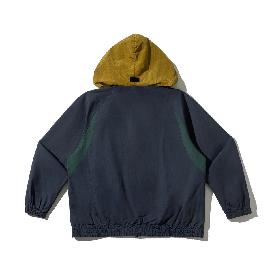 Back view of a dark navy hooded jacket with a mustard hood, green side panels, and elastic cuffs and hem.