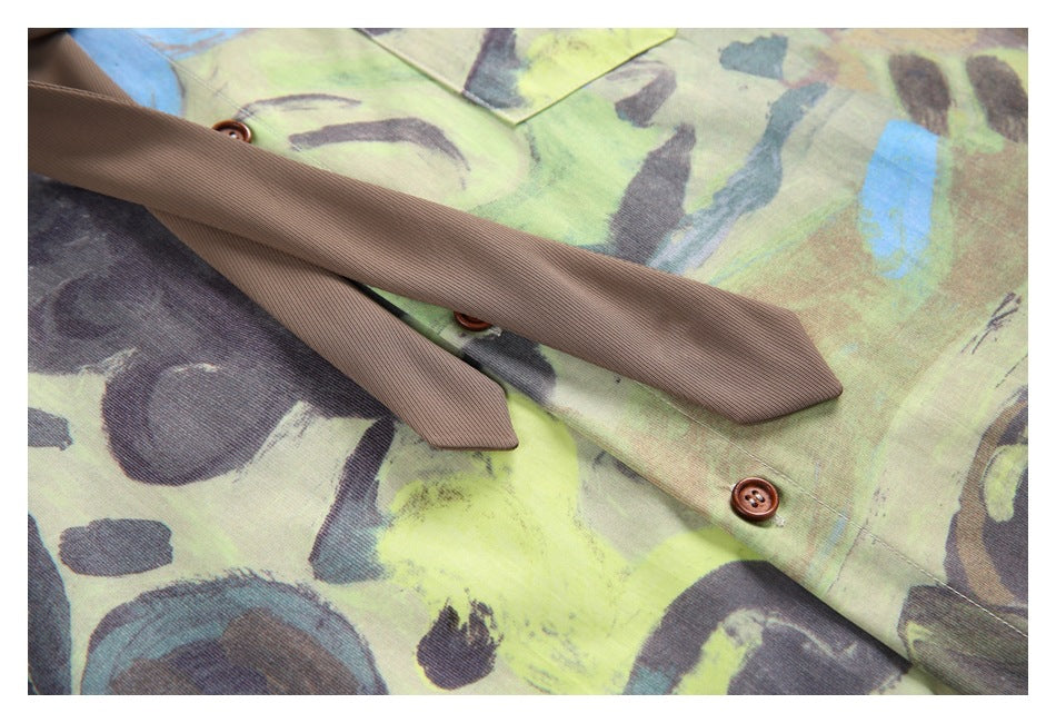 Close-up of a brown necktie laid across the abstract-print shirt, showing brown buttons.