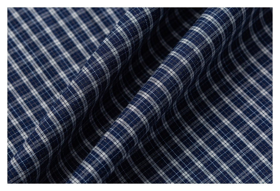 Close-up of folded navy fabric showing a fine white and gray plaid pattern.