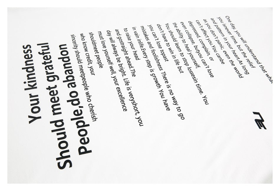 Close-up of a white T-shirt printed with black English text and a small geometric mark.