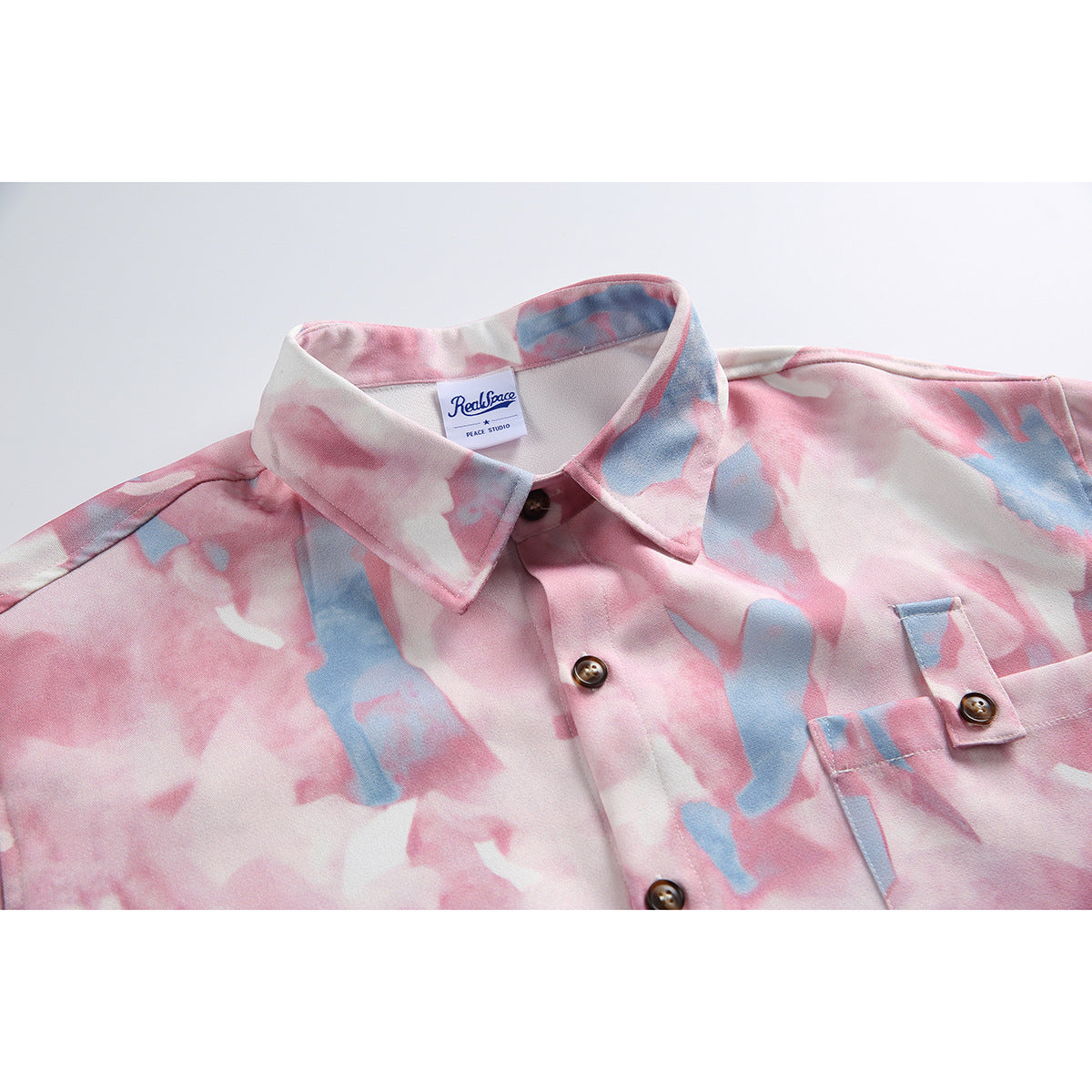 Close-up of the shirt’s pink and blue abstract print, pointed collar, brown buttons, and chest pocket.