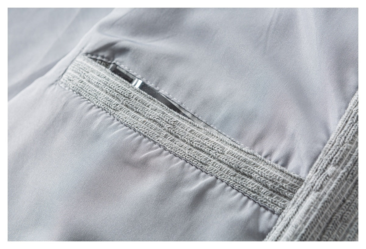 Close-up of a light gray garment pocket with thick textured trim and a small metal zipper pull.