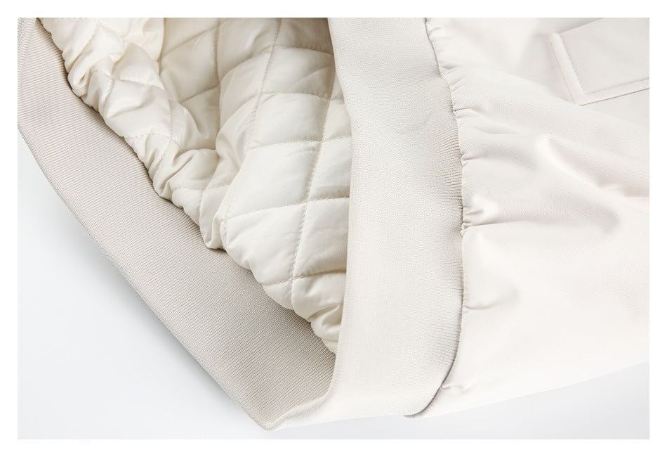 Close-up of the ivory jacket's quilted lining, gathered edge, and ribbed hem band.