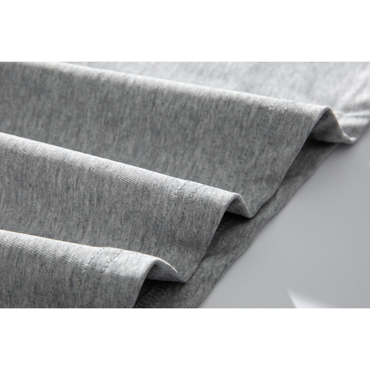 Close-up of folded gray T-shirt fabric showing a stitched hem.