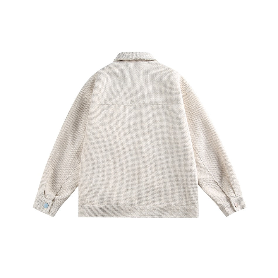 Back view of an ivory textured jacket laid flat, showing a plain back, collar, long sleeves, and buttoned cuffs.