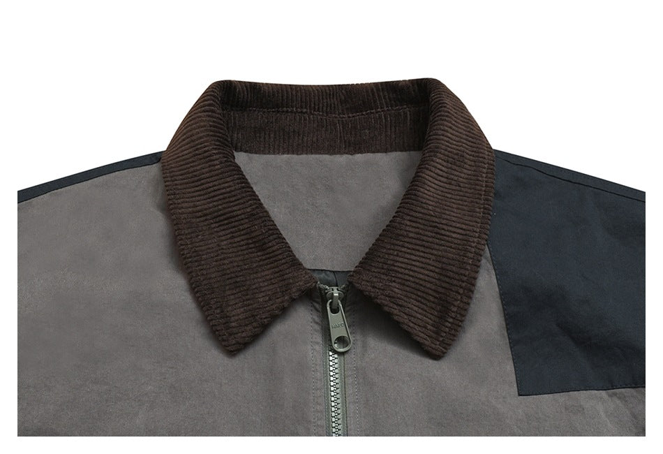 Close-up of a gray jacket's upper front, showing its ribbed brown collar, zipper, and navy shoulder panel.