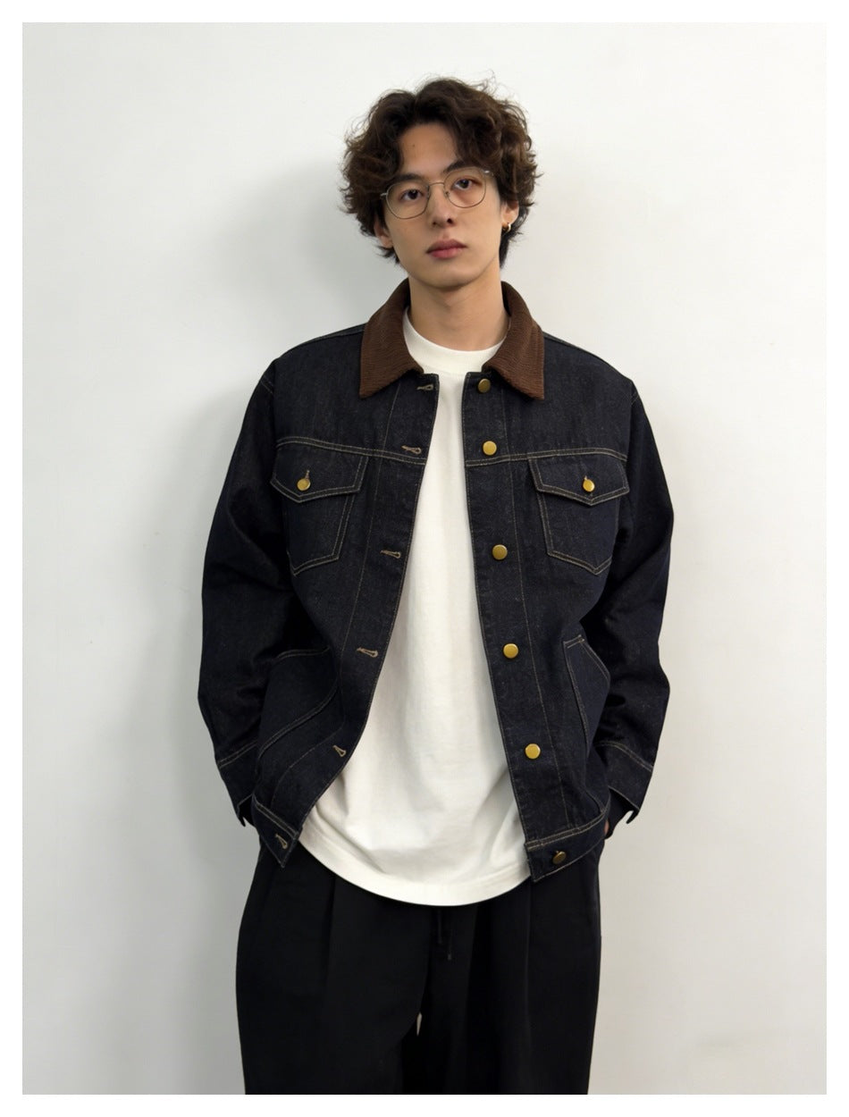 Model wearing open dark denim jacket with brown collar over white tee and black trousers, front view