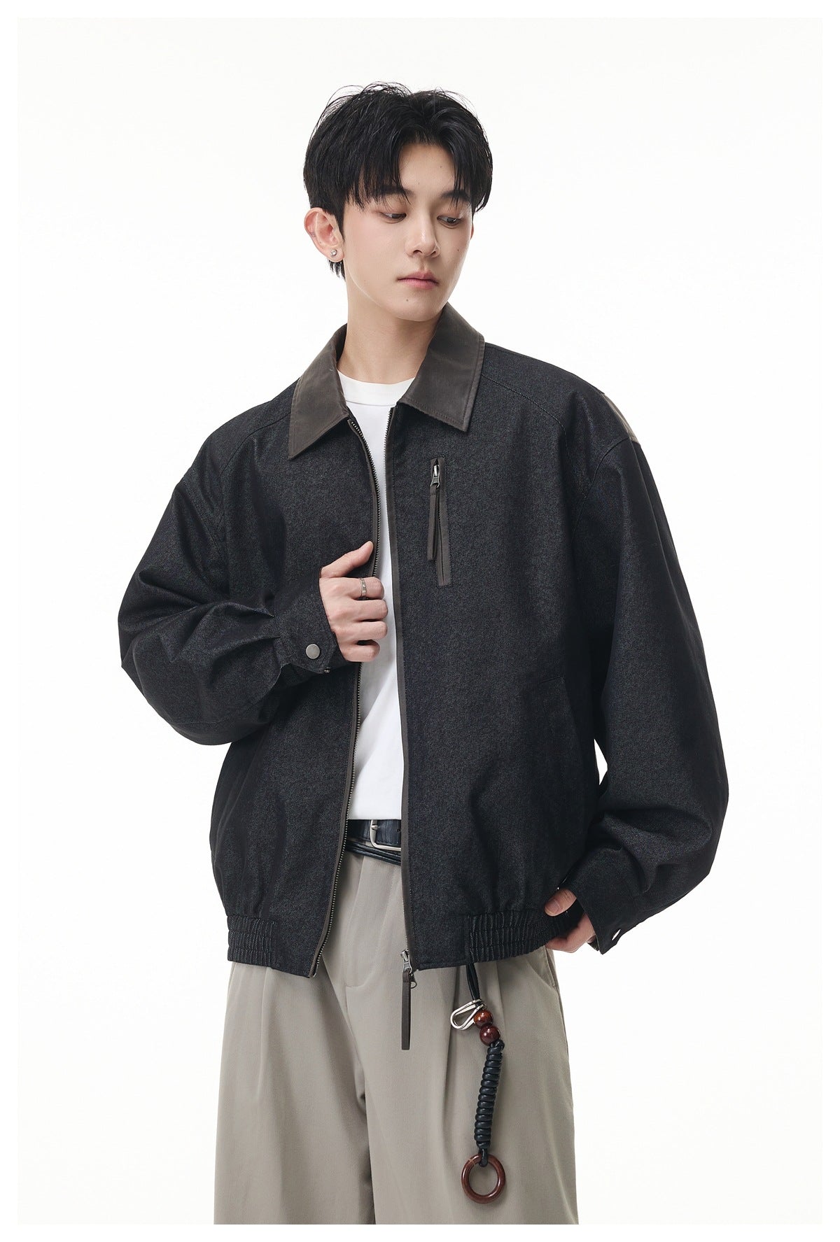 Front view of a model wearing a charcoal zip jacket with a contrasting collar, chest pocket and elastic hem.
