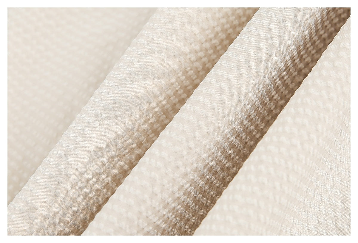 Close-up of softly folded ivory fabric showing its small raised woven texture.