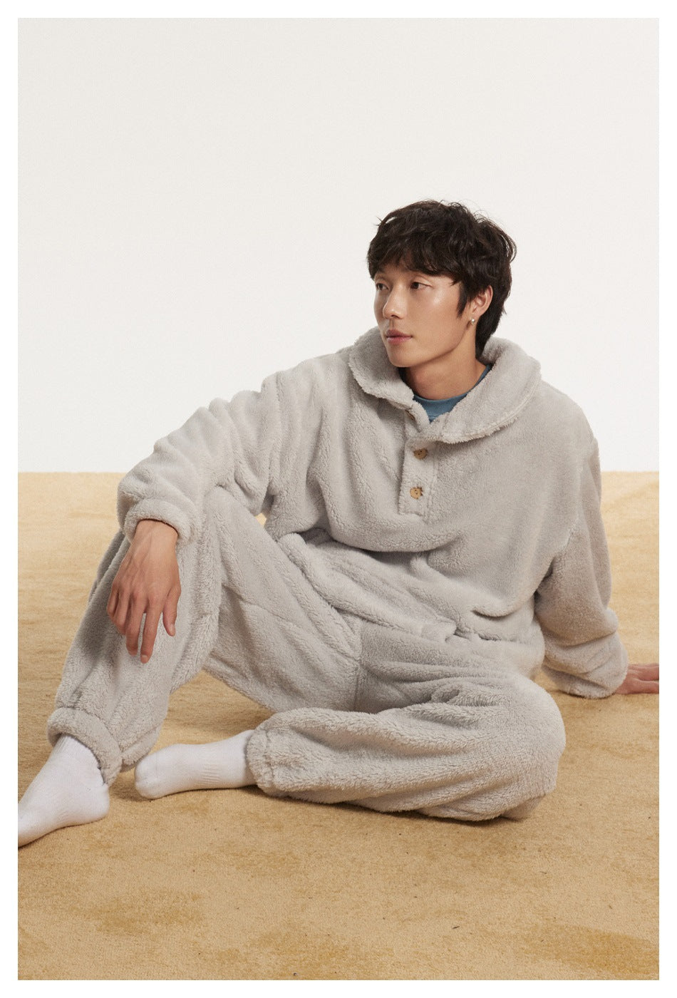 Model seated in a light gray plush pullover with a wide collar and matching pants.