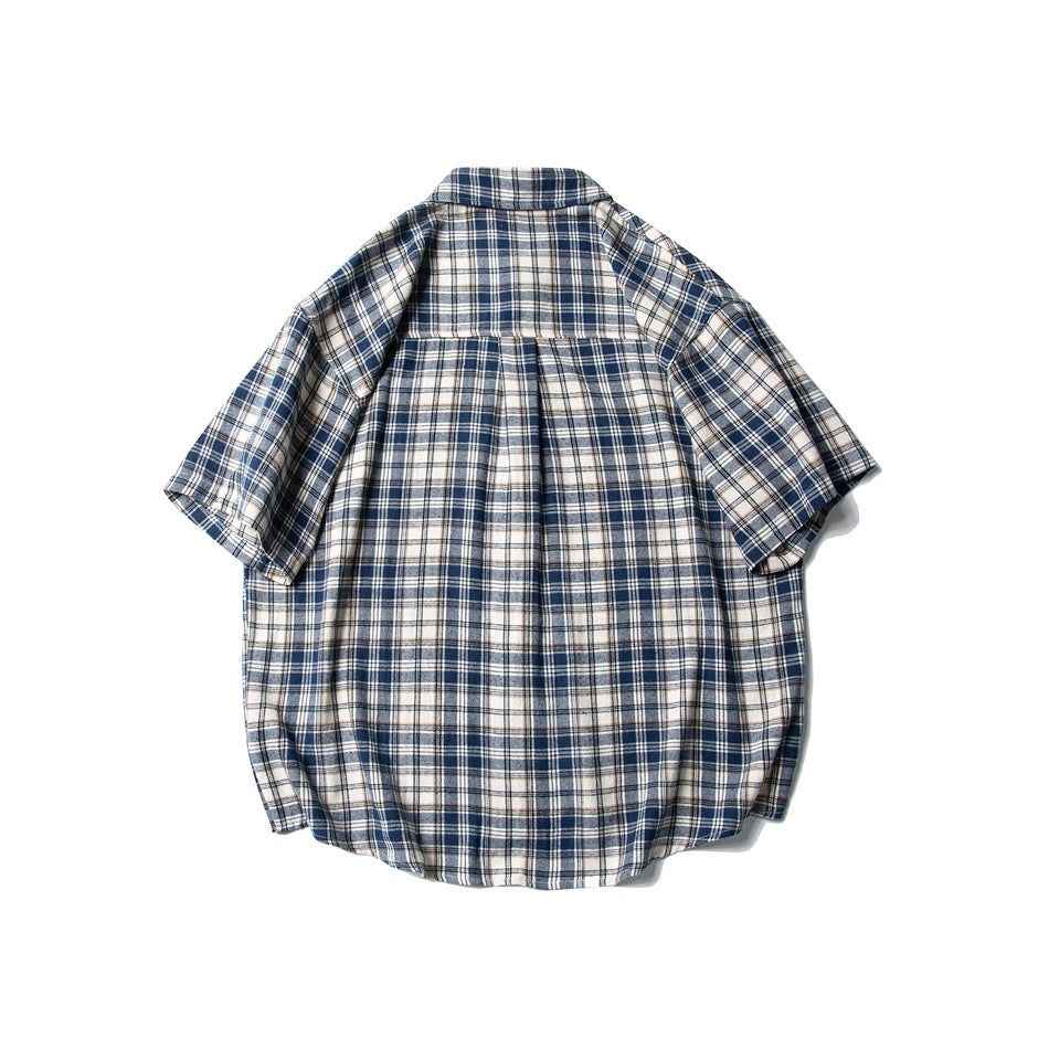 Back view of navy, cream and white plaid short-sleeve shirt with yoke seam and center pleat, laid flat