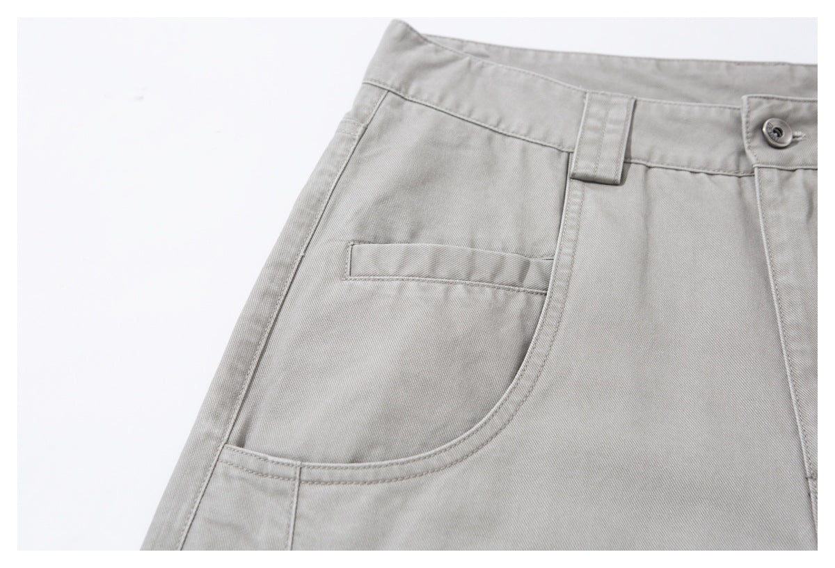 Close-up of light gray trousers showing a curved front pocket and a small inset pocket.