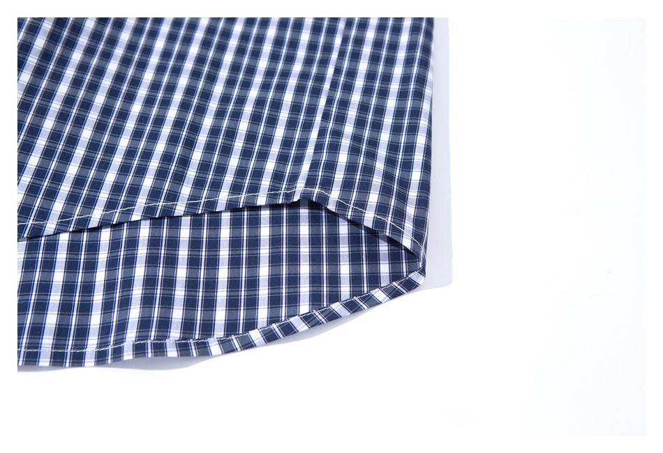 Close-up of the curved hem of a navy, white, and gray plaid shirt.