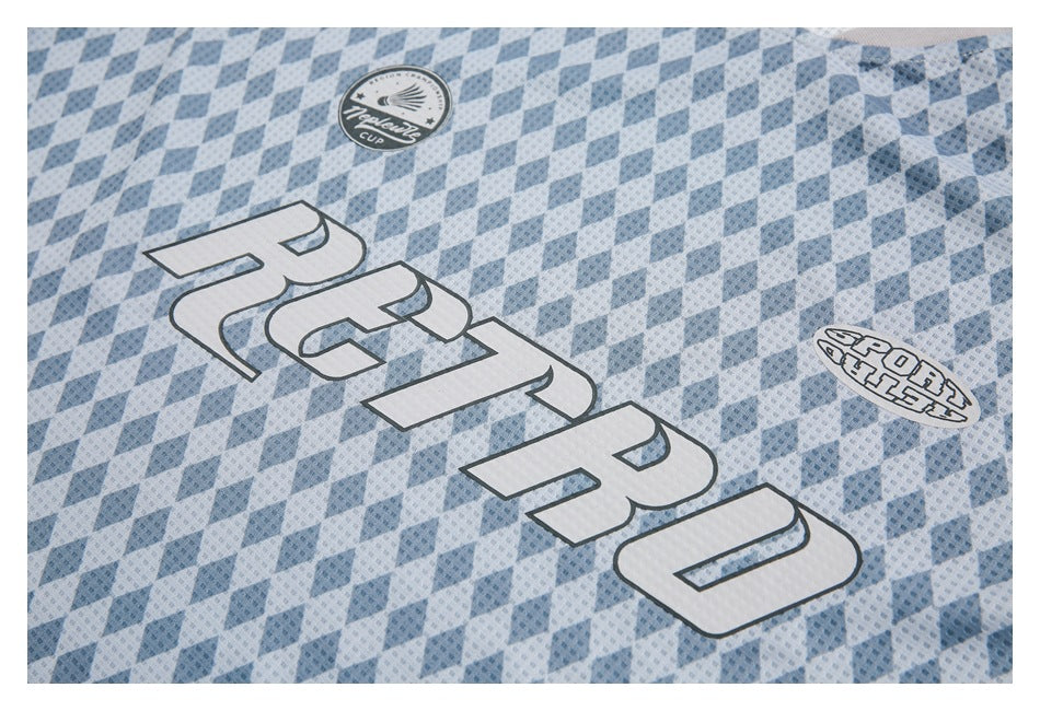 Close-up of a blue diamond-patterned jersey with large white outlined lettering and small chest emblems.