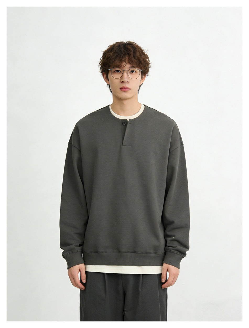 Front view of a model wearing a charcoal oversized sweatshirt with a single-button placket.