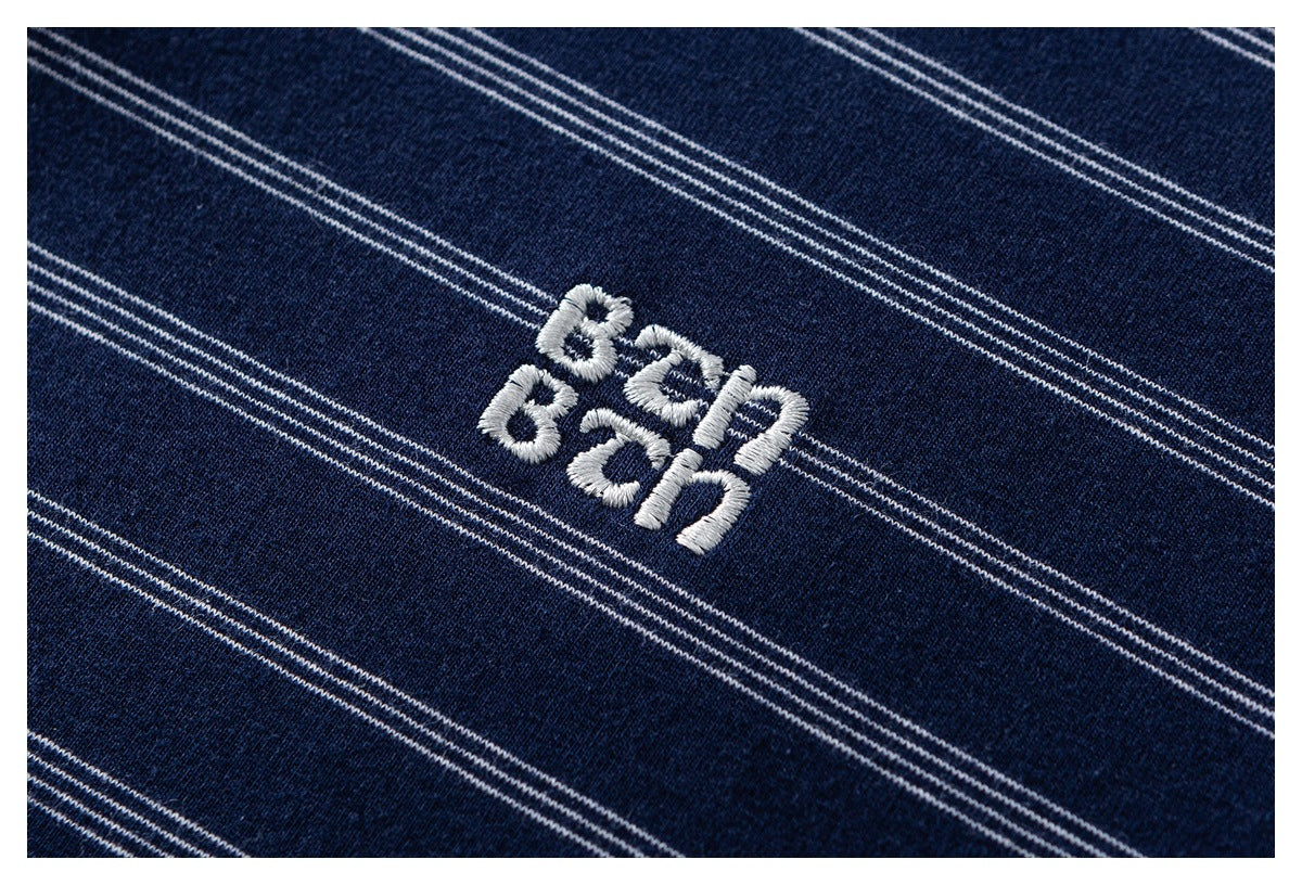 Close-up of white embroidered lettering on navy fabric with thin white stripes.