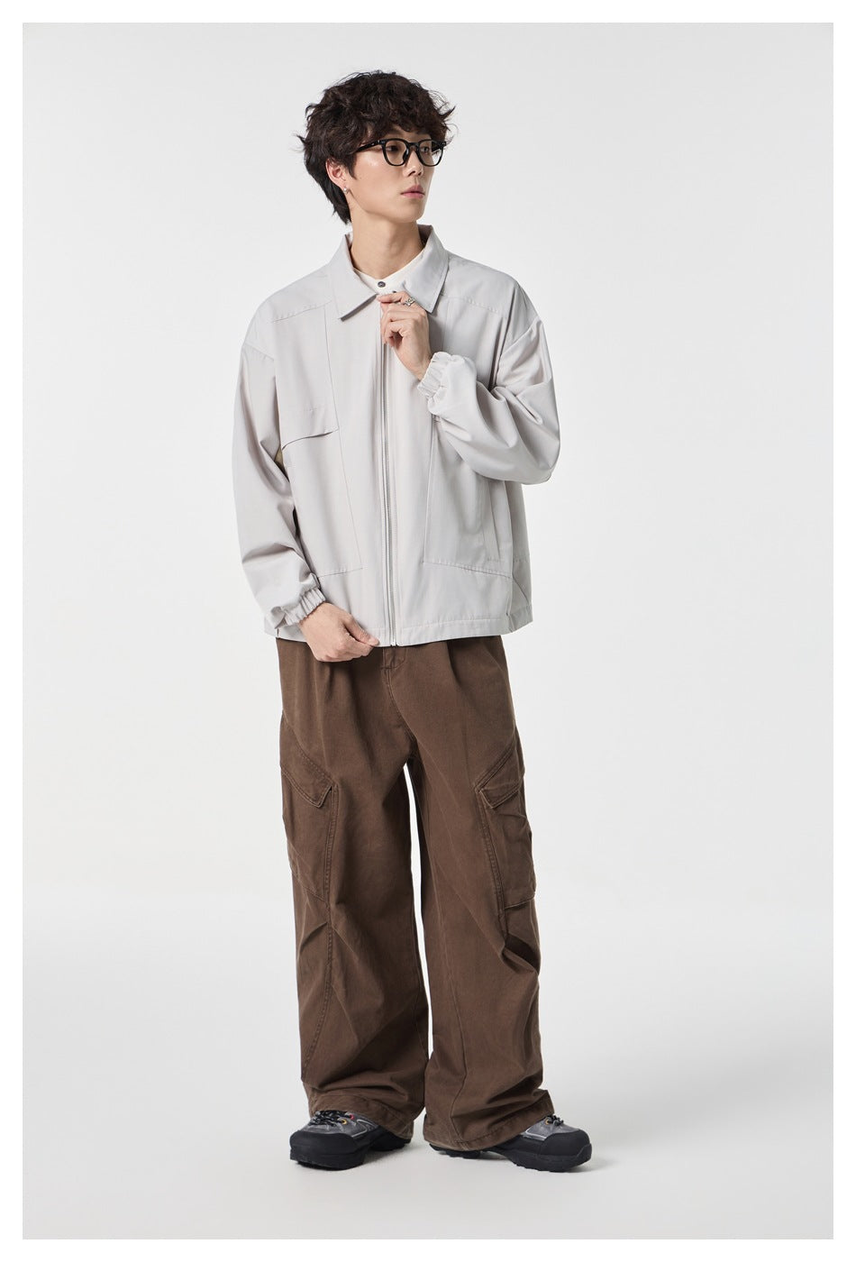 Model wearing a beige zip-up collared jacket over a white top with brown wide-leg cargo pants and sneakers