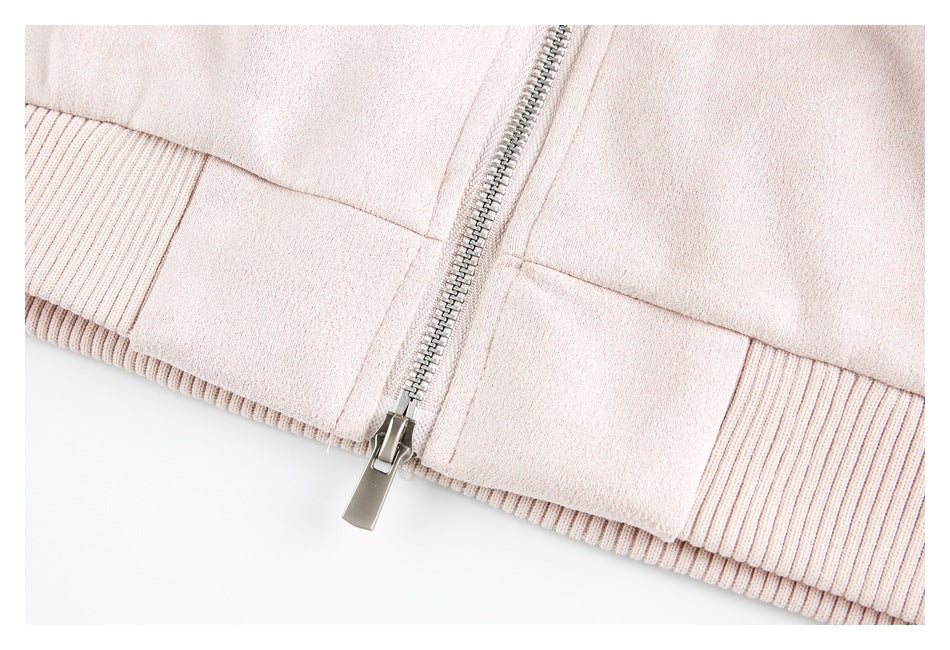 Close-up of a pale blush-pink garment with a silver zipper and ribbed hem.