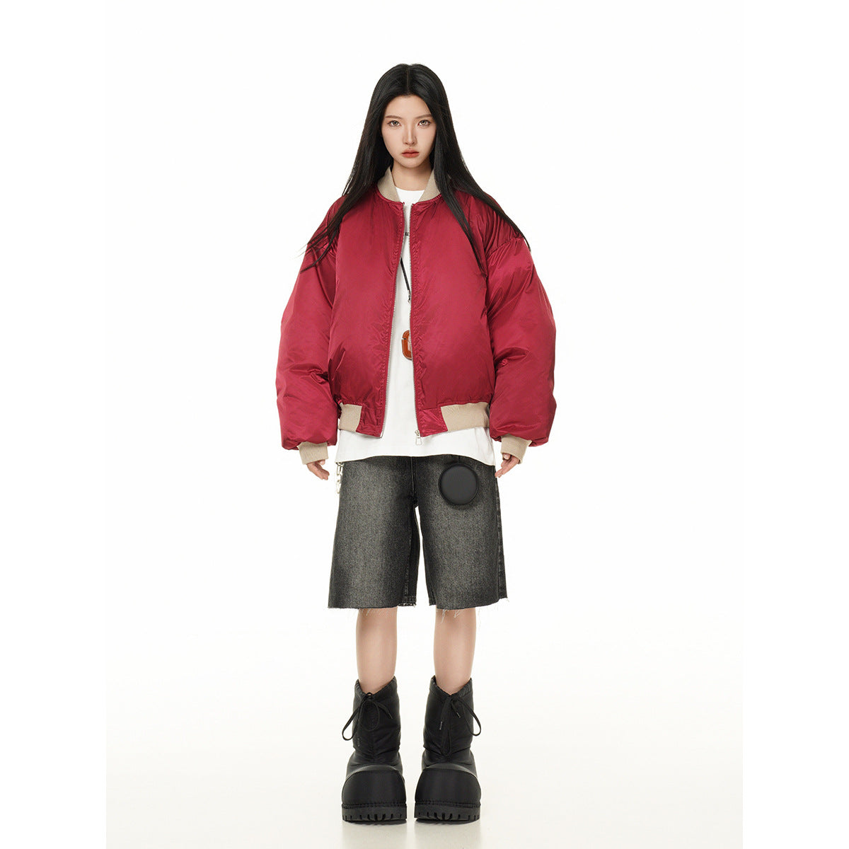Full-length model wearing a red oversized bomber jacket with beige ribbed trim, a white top and dark shorts.