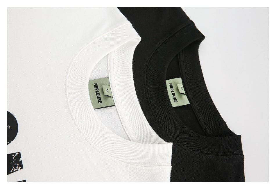 Close-up of overlapping white and black T-shirt collars with green neck labels.