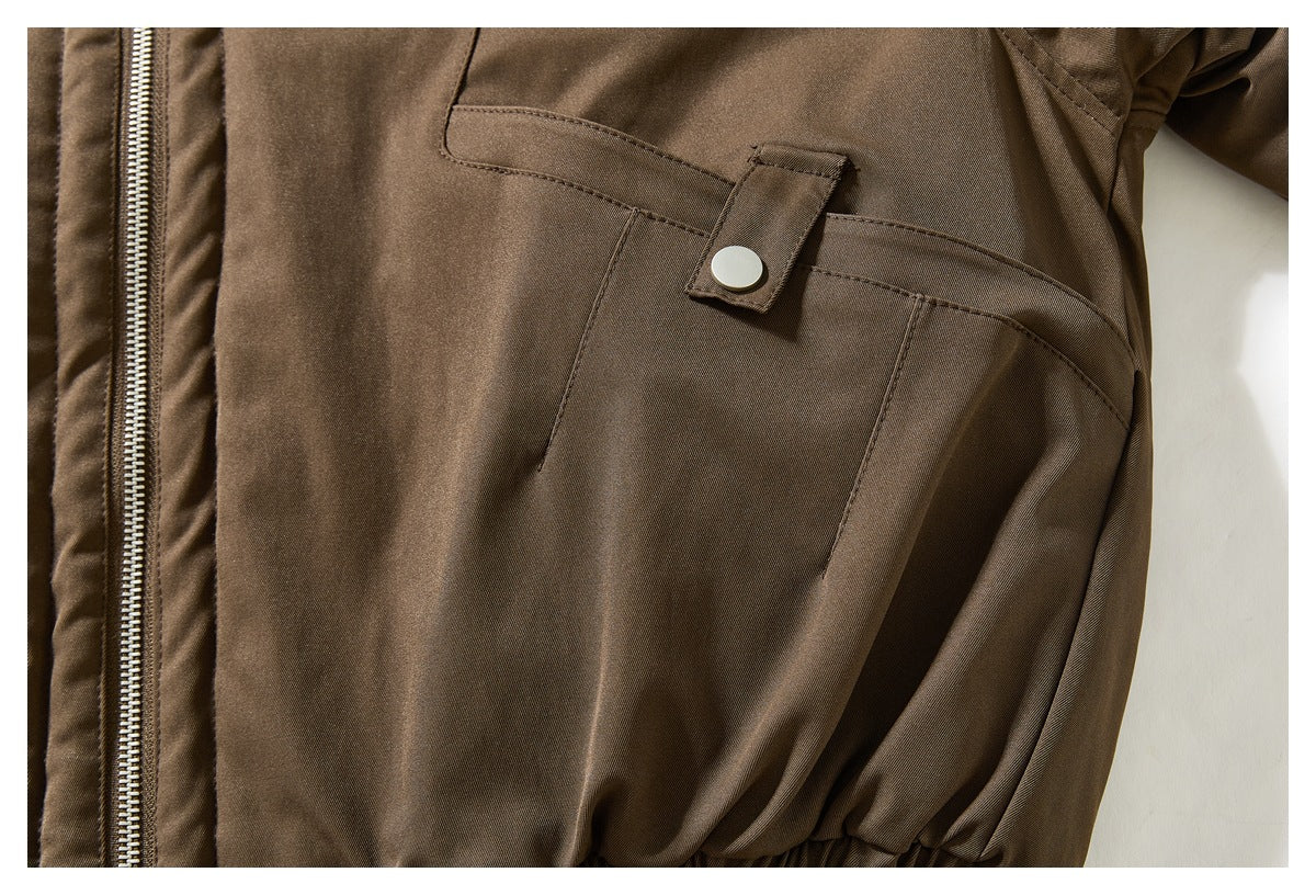 Close-up of a brown jacket pocket with a snap tab and the front zipper beside it.