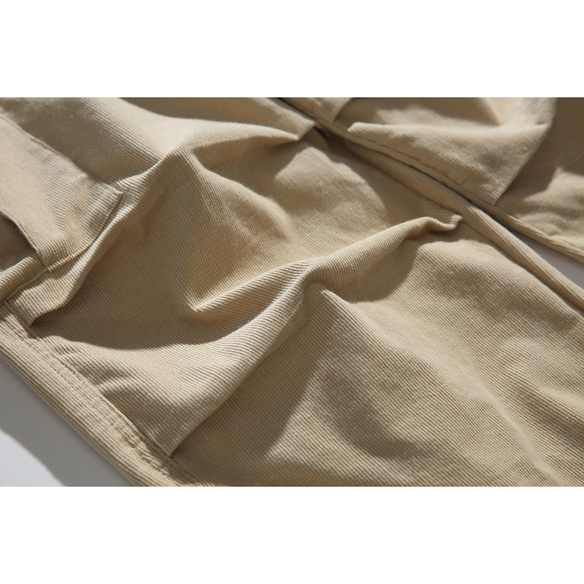 Close-up of the beige pants' ribbed fabric and stitched seams.