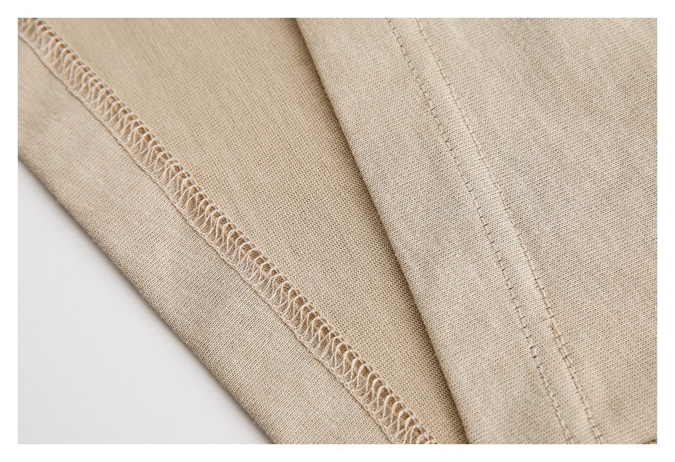 Close-up of beige garment fabric showing an overlocked seam and parallel stitching.