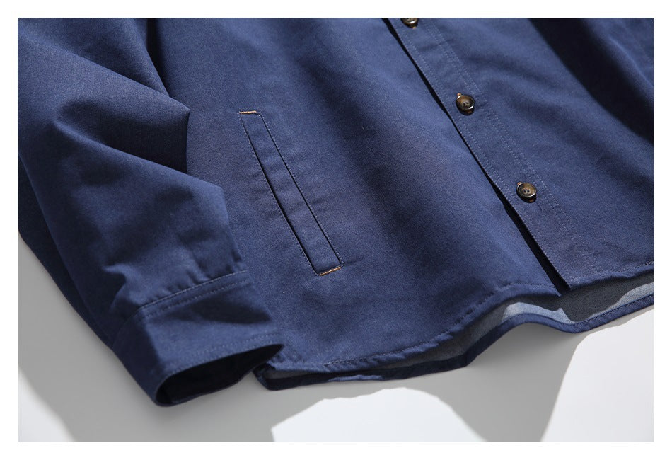 Close-up of the navy shirt’s lower front, showing a slim pocket, button placket and curved hem.