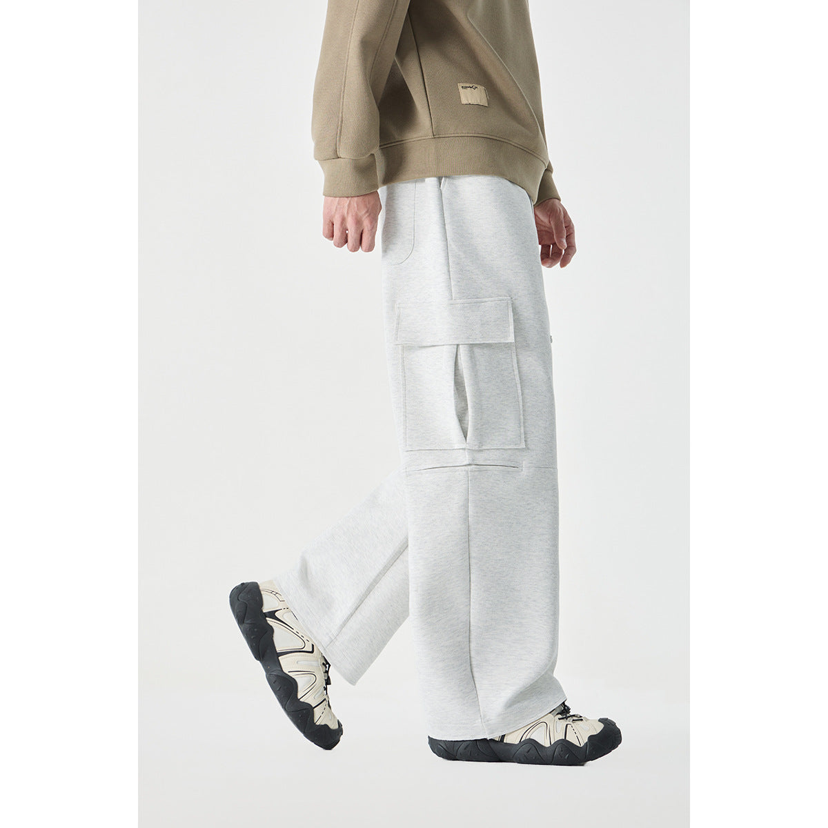 Side view of a model wearing light gray wide-leg cargo pants with a large flap pocket.