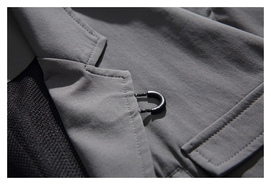 Close-up of the charcoal jacket's lapel edge, stitching, and small black metal loop.