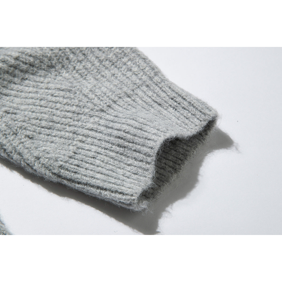 Close-up of the ribbed cuff of a light gray knit sweater.