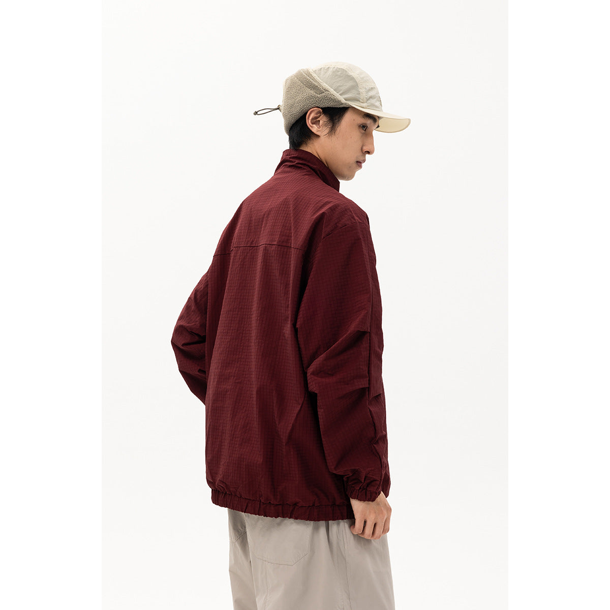 Model in a burgundy high-collar jacket, shown from the back in a three-quarter view.