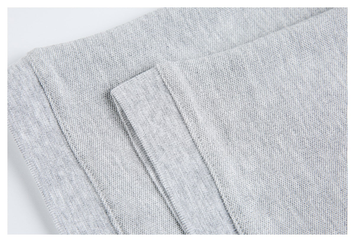 Close-up of overlapping light gray knit fabric panels and their stitched edges.