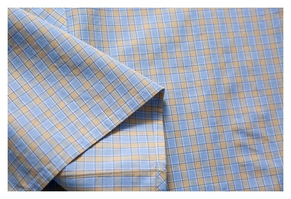 Close-up of the shirt's blue and tan plaid fabric and folded hem.